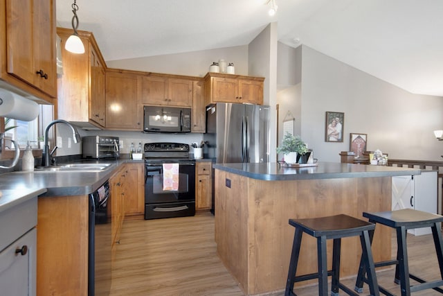 1105 Pioneer Trl SE, Cambridge, MN 55008 - kitchen with black appliances, vaulted ceiling, dark countertops, light wood-style floors, and a breakfast bar