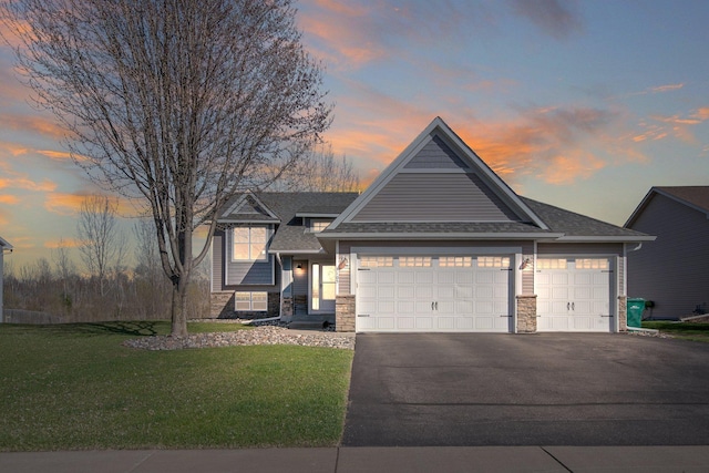 1105 Pioneer Trl SE, Cambridge, MN 55008 - view of front of home featuring stone siding, an attached garage, asphalt driveway, a lawn, and roof with shingles