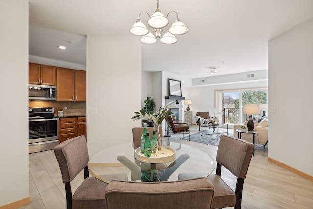 10806 Shore Dr Unit 103, Plymouth, MN 55441 - dining room featuring a chandelier, light wood-style floors, a glass covered fireplace, and recessed lighting