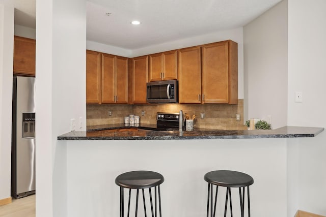 10806 Shore Dr Unit 103, Plymouth, MN 55441 - kitchen with stainless steel appliances, dark stone counters, decorative backsplash, brown cabinets, and recessed lighting
