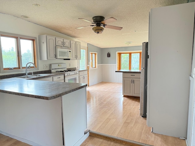 110 9th Ave NE, Deer River, MN 56636 - kitchen with white appliances, a sink, a peninsula, a textured ceiling, and light wood-style floors