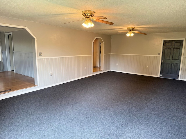 110 9th Ave NE, Deer River, MN 56636 - carpeted empty room featuring ceiling fan, a wainscoted wall, a textured ceiling, and arched walkways