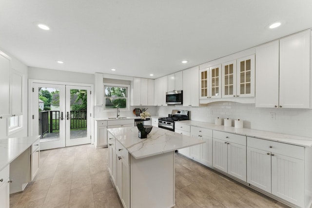 1032 Scheffer Ave, Saint Paul, MN 55102 - kitchen with stainless steel appliances, a sink, white cabinetry, a center island, and light stone counters