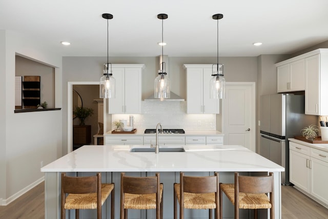 19648 104th Pl, Corcoran, MN 55374 - kitchen with exhaust hood, light wood finished floors, tasteful backsplash, a sink, and a kitchen bar