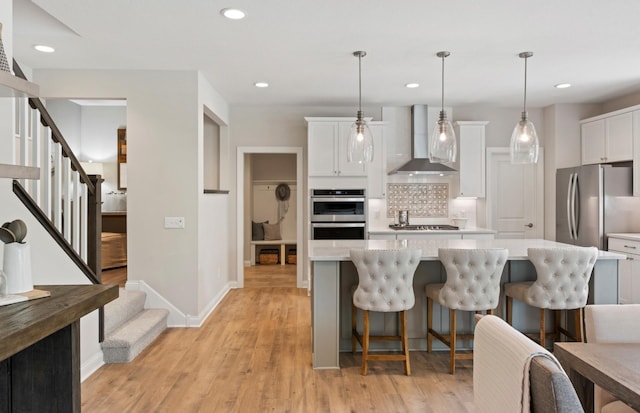 19648 104th Pl, Corcoran, MN 55374 - kitchen featuring wall chimney range hood, stainless steel appliances, tasteful backsplash, a kitchen island, and light countertops