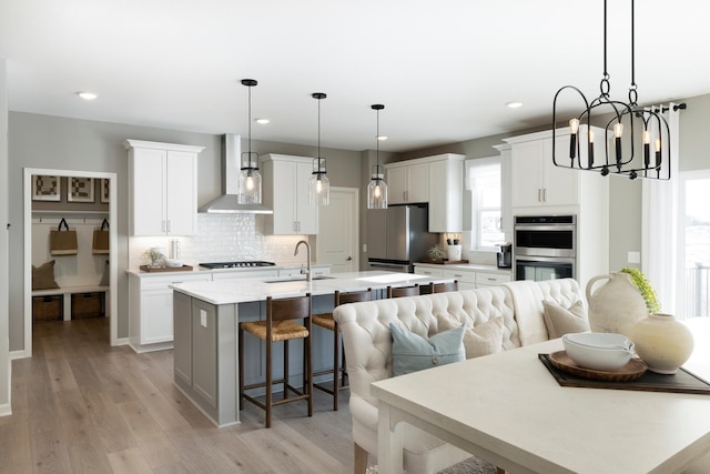 19648 104th Pl, Corcoran, MN 55374 - kitchen with wall chimney range hood, appliances with stainless steel finishes, a kitchen breakfast bar, decorative backsplash, and a center island with sink