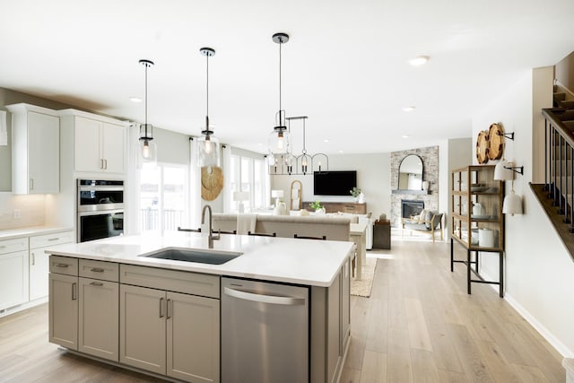 19648 104th Pl, Corcoran, MN 55374 - kitchen featuring stainless steel appliances, a sink, a center island with sink, light countertops, and gray cabinets