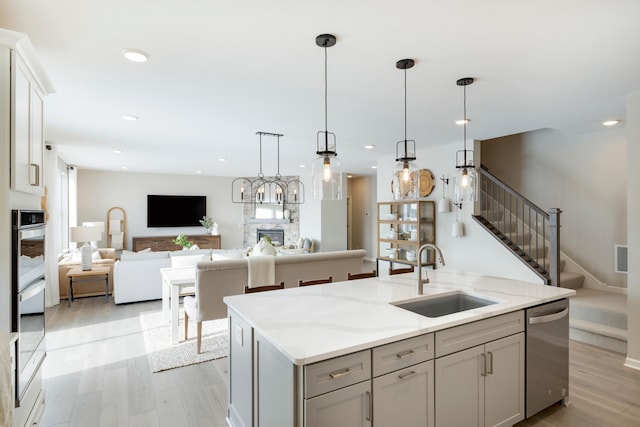 19648 104th Pl, Corcoran, MN 55374 - kitchen featuring a sink, stainless steel dishwasher, open floor plan, light wood finished floors, and a kitchen island with sink