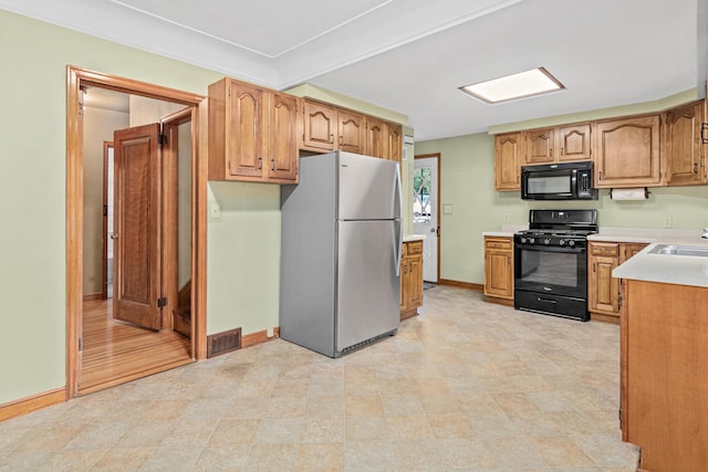 148 5th Ave N, Hopkins, MN 55343 - kitchen featuring black appliances, light countertops, and brown cabinetry