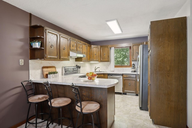 1060 Greer Ave NW, Albion Twp, MN 55358 - kitchen with appliances with stainless steel finishes, under cabinet range hood, a peninsula, light countertops, and tasteful backsplash