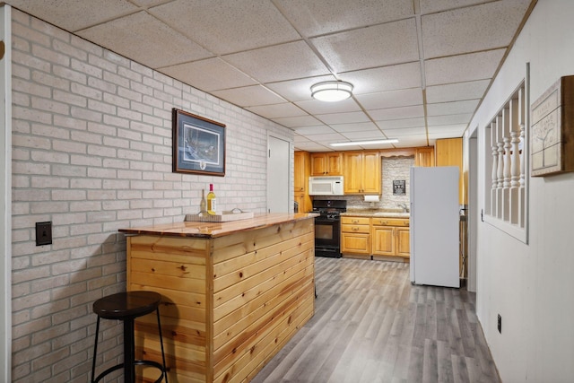 1060 Greer Ave NW, Albion Twp, MN 55358 - kitchen with white appliances, a drop ceiling, light wood-style flooring, brick wall, and a sink