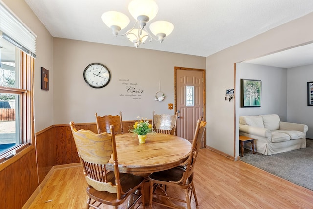 3513 Adair Ave N, Crystal, MN 55422 - dining room featuring a chandelier, healthy amount of natural light, light wood-style floors, a wainscoted wall, and wooden walls