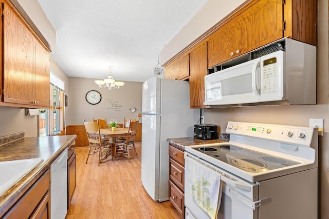 3513 Adair Ave N, Crystal, MN 55422 - kitchen featuring white appliances, a chandelier, brown cabinetry, light wood-type flooring, and a sink