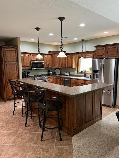 23567 Timber Trail Dr, Bemidji, MN 56601 - kitchen with appliances with stainless steel finishes, a large island, dark countertops, recessed lighting, and decorative light fixtures