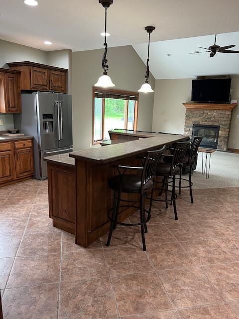 23567 Timber Trail Dr, Bemidji, MN 56601 - kitchen with stainless steel refrigerator with ice dispenser, a stone fireplace, a breakfast bar, lofted ceiling, and decorative light fixtures