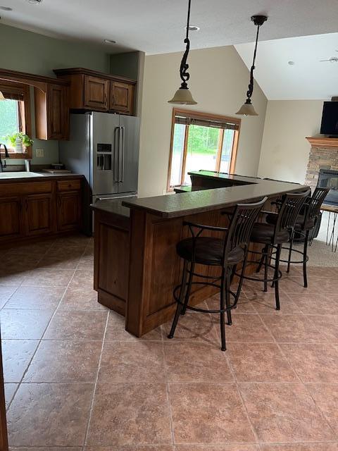 23567 Timber Trail Dr, Bemidji, MN 56601 - kitchen featuring a sink, stainless steel refrigerator with ice dispenser, dark countertops, light tile patterned floors, and lofted ceiling