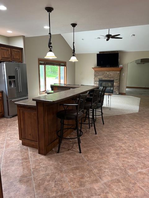 23567 Timber Trail Dr, Bemidji, MN 56601 - kitchen featuring high end refrigerator, a ceiling fan, dark countertops, vaulted ceiling, and a kitchen breakfast bar