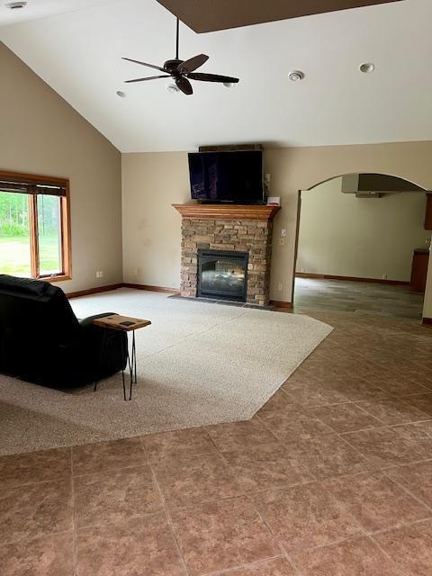 23567 Timber Trail Dr, Bemidji, MN 56601 - tiled living area featuring high vaulted ceiling, ceiling fan, arched walkways, a fireplace, and baseboards