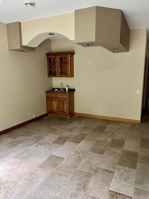 23567 Timber Trail Dr, Bemidji, MN 56601 - bar area with baseboards, arched walkways, a sink, and light stone finish floors