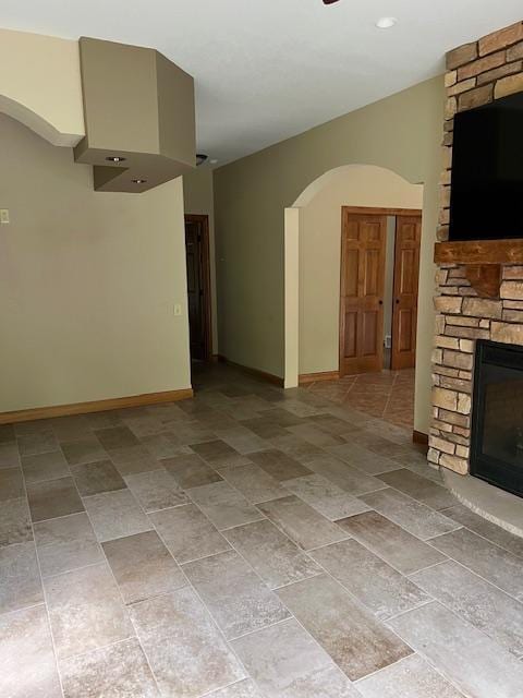 23567 Timber Trail Dr, Bemidji, MN 56601 - empty room featuring arched walkways, a stone fireplace, and baseboards
