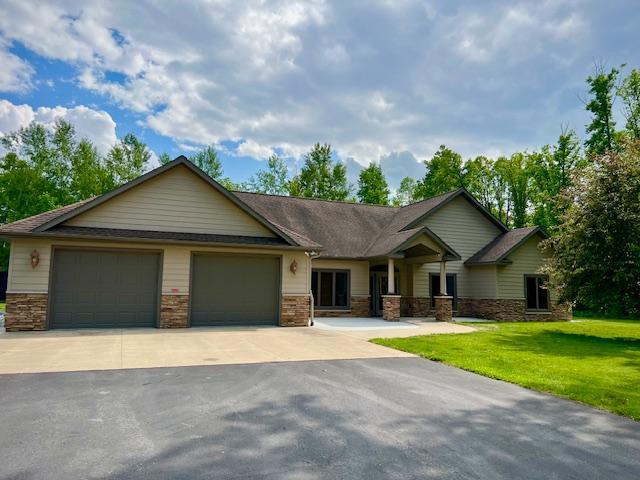 23567 Timber Trail Dr, Bemidji, MN 56601 - view of front of home featuring driveway, a front yard, an attached garage, and stone siding