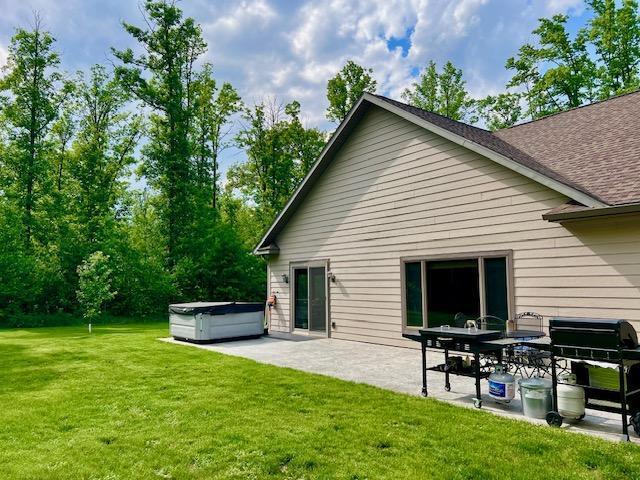 23567 Timber Trail Dr, Bemidji, MN 56601 - back of property with a hot tub, a patio, a lawn, and a shingled roof
