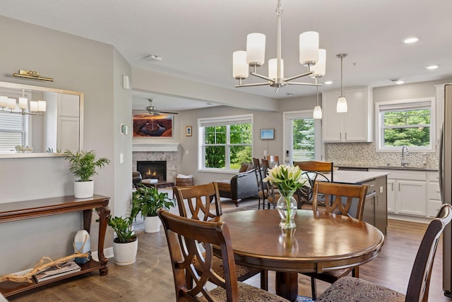 13824 102nd Pl N, Maple Grove, MN 55369 - dining area featuring a chandelier, wood finished floors, a fireplace, a ceiling fan, and recessed lighting