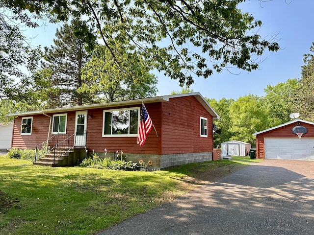 303 Goad Dr, Wrenshall, MN 55797 - view of front of house with a detached garage, a front lawn, and a storage shed