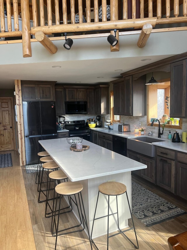 454 Wagon Wheel Dr SE Unit 17, Ten Lake Twp, MN 56601 - kitchen with black appliances, a kitchen breakfast bar, light wood-style floors, a center island, and light stone countertops
