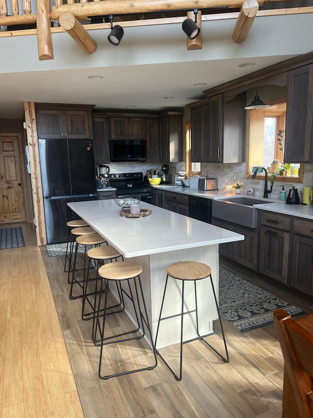 454 Wagon Wheel Dr SE Unit 17, Ten Lake Twp, MN 56601 - kitchen with black appliances, light wood-style floors, light countertops, a kitchen breakfast bar, and a center island