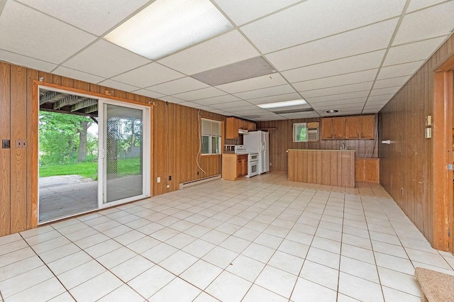 43394 Long Lake Ln, Ottertail, MN 56571 - kitchen featuring a baseboard radiator, wood walls, brown cabinetry, freestanding refrigerator, and a drop ceiling