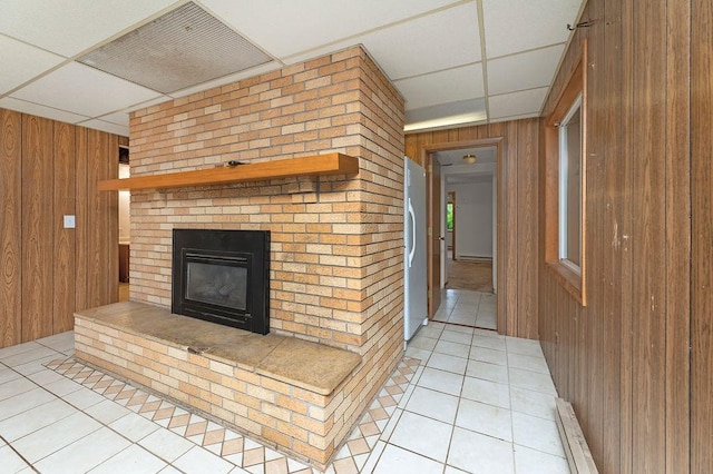 43394 Long Lake Ln, Ottertail, MN 56571 - unfurnished living room with wood walls, light tile patterned floors, a paneled ceiling, a brick fireplace, and baseboard heating