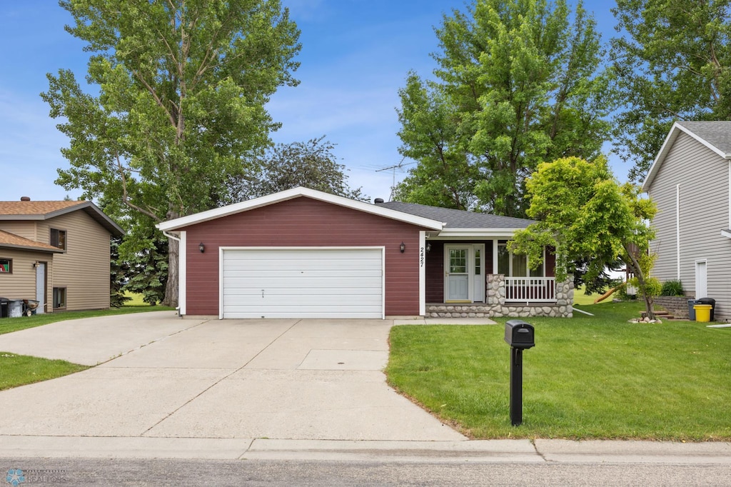 2427 33rd Ave S, Moorhead, MN 56560 - view of front of house featuring covered porch, driveway, a front lawn, and a garage