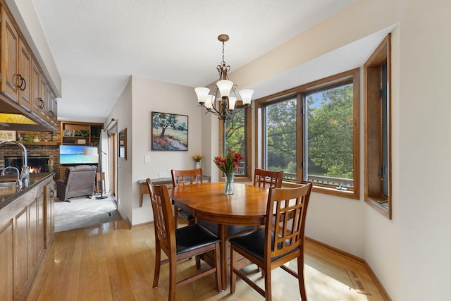 14023 Yellow Pine St NW, Andover, MN 55304 - dining area featuring light wood-style flooring, a brick fireplace, and a chandelier