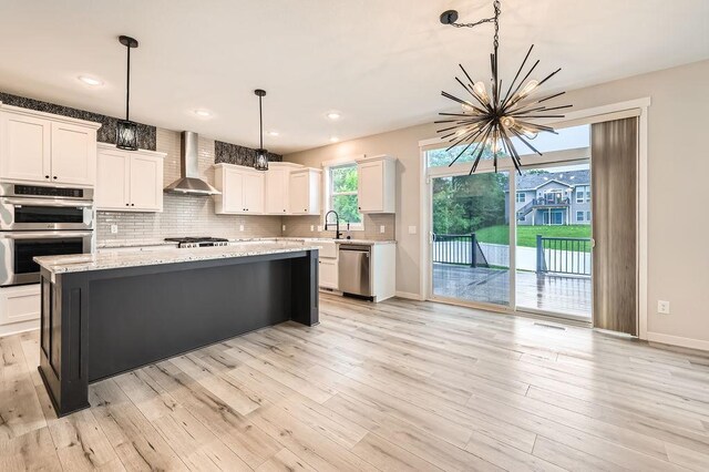 139 144th Ave NW, Andover, MN 55304 - kitchen with wall chimney range hood, appliances with stainless steel finishes, a chandelier, decorative backsplash, and white cabinets