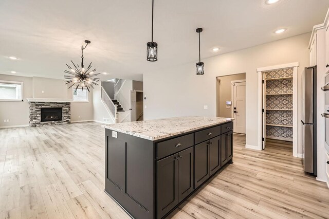 139 144th Ave NW, Andover, MN 55304 - kitchen featuring light wood-style floors, a kitchen island, light stone counters, decorative light fixtures, and freestanding refrigerator