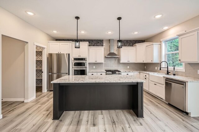 139 144th Ave NW, Andover, MN 55304 - kitchen featuring appliances with stainless steel finishes, wall chimney exhaust hood, tasteful backsplash, a center island, and white cabinetry