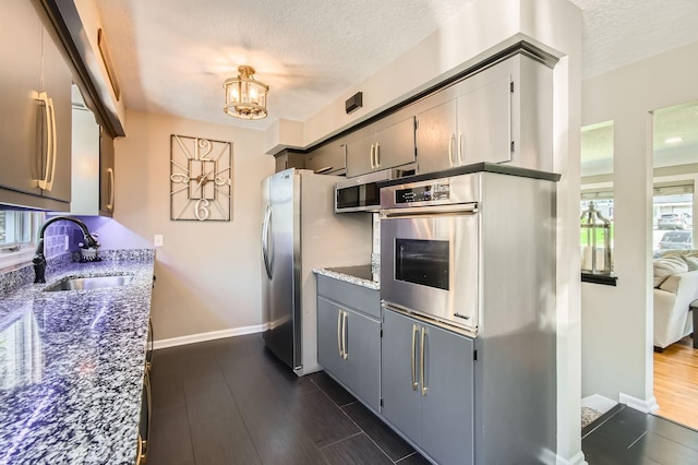 13812 Steven Rd, Burnsville, MN 55337 - kitchen featuring a sink, a textured ceiling, appliances with stainless steel finishes, stone countertops, and baseboards