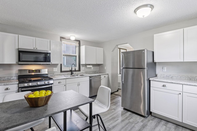 4718 Colfax Ave N, Minneapolis, MN 55430 - kitchen featuring appliances with stainless steel finishes, light wood-type flooring, light countertops, a textured ceiling, and white cabinetry