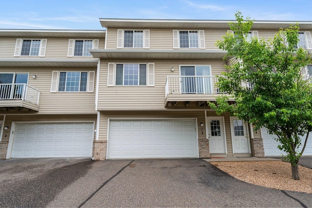 1587 County Road D E Unit B, Maplewood, MN 55109 - view of property featuring driveway, an attached garage, a balcony, and brick siding