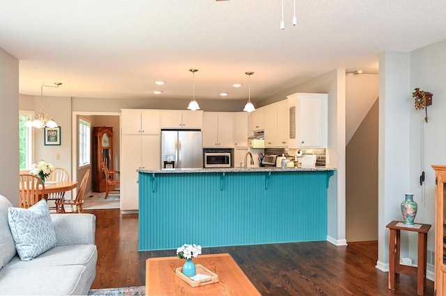 6490 White Dove Dr, Excelsior, MN 55331 - kitchen with stainless steel appliances, a peninsula, white cabinetry, dark wood-style flooring, and light stone counters