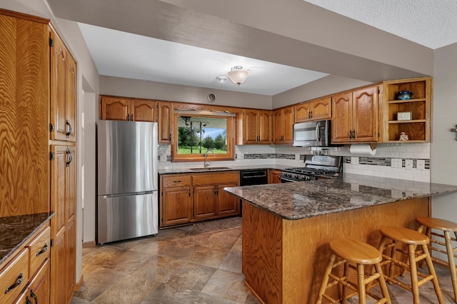 1341 75th Ave NE, Sauk Rapids, MN 56379 - kitchen featuring stainless steel appliances, brown cabinets, a peninsula, dark stone countertops, and decorative backsplash