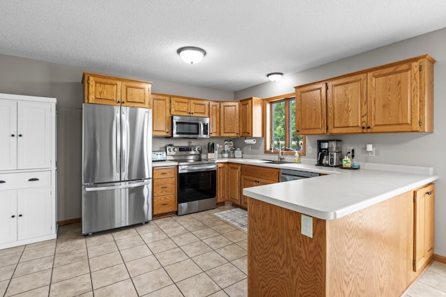 32147 111 1/2 St, Baldwin Twp, MN 55371 - kitchen featuring appliances with stainless steel finishes, a sink, a peninsula, light countertops, and brown cabinetry