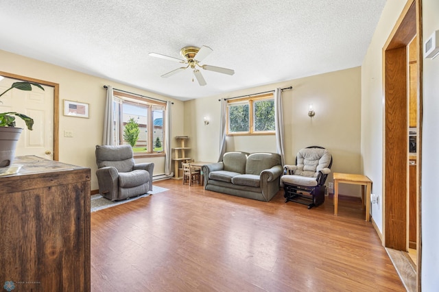 1307 5th St S, Fargo, ND 58103 - living room featuring light wood-style flooring, ceiling fan, a textured ceiling, and a baseboard heating unit