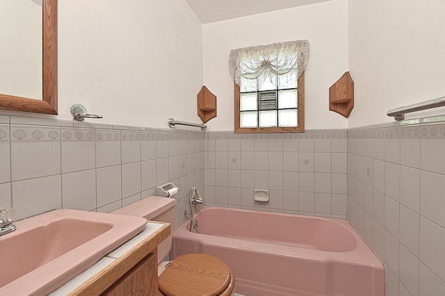 619 9th Ave, Grand Rapids, MN 55744 - bathroom featuring a garden tub, tile walls, toilet, vanity, and wainscoting