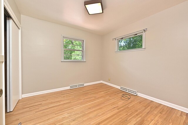 619 9th Ave, Grand Rapids, MN 55744 - unfurnished bedroom with multiple windows, baseboards, light wood-style flooring, and a closet