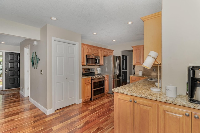 4078 153rd St W, Rosemount, MN 55068 - kitchen with stainless steel appliances, tasteful backsplash, light wood-type flooring, recessed lighting, and light stone counters
