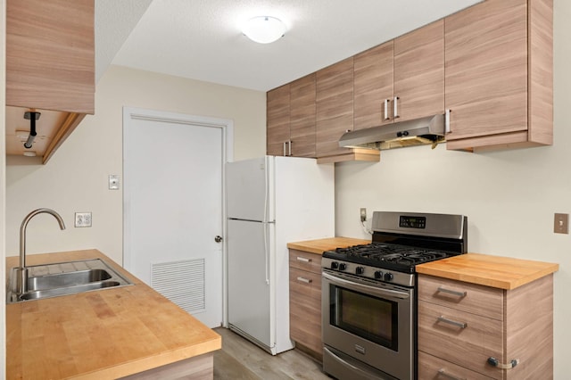 2783 Upland Ct, Plymouth, MN 55447 - kitchen featuring stainless steel range with gas stovetop, butcher block countertops, under cabinet range hood, light wood-type flooring, and freestanding refrigerator