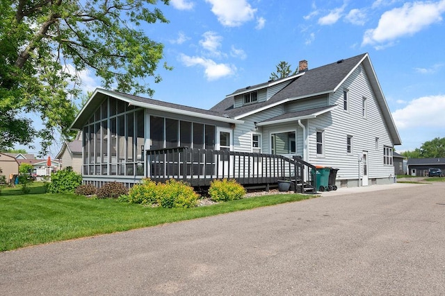 115 Spruce St W, Grey Eagle, MN 56336 - view of front of home featuring a sunroom, a shingled roof, a chimney, a front lawn, and a wooden deck