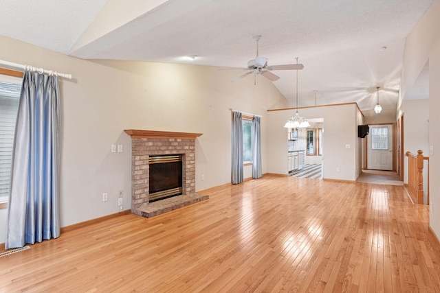 1040 Primrose Ln, Waconia, MN 55387 - unfurnished living room featuring lofted ceiling, ceiling fan, light wood-type flooring, a fireplace, and a chandelier